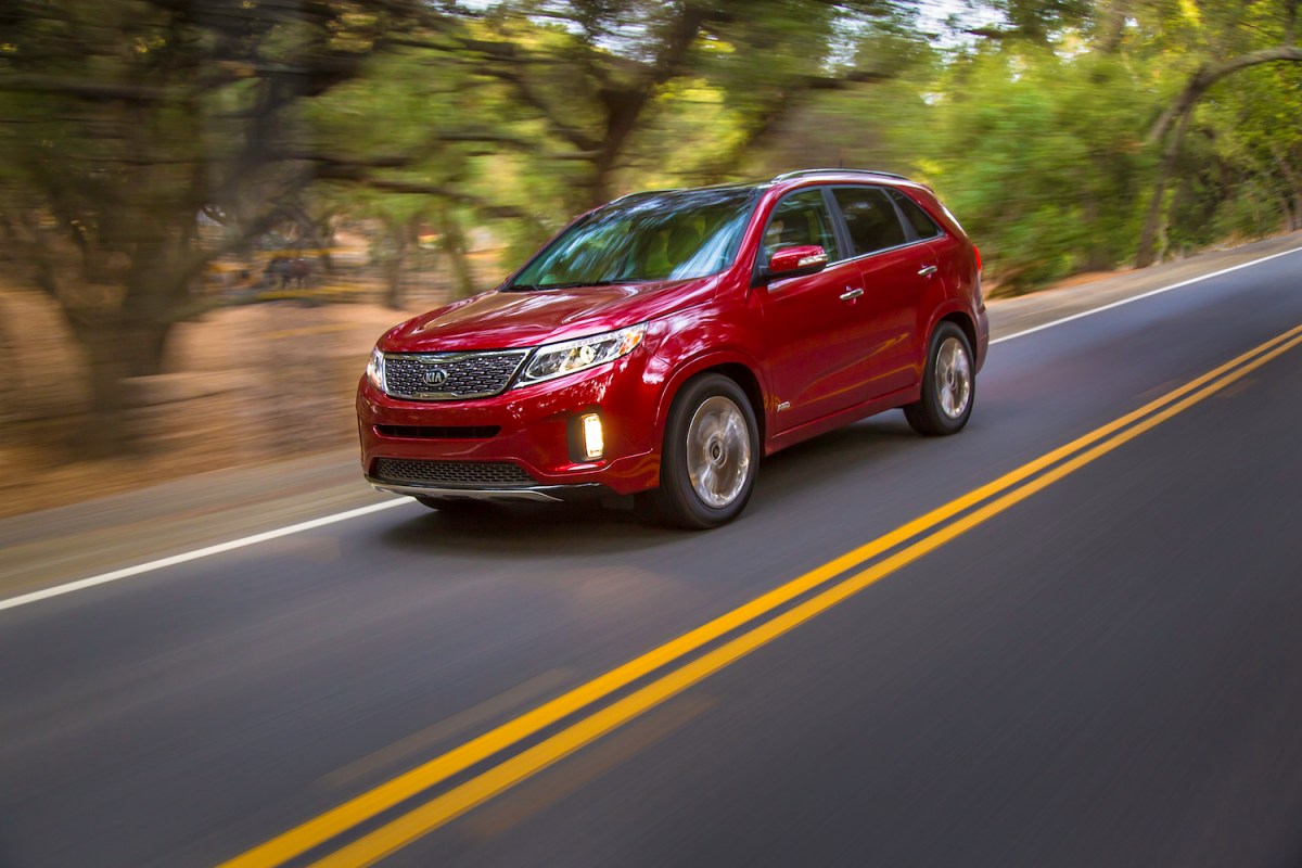 A red 2014 Kia Sorento used midsize SUV driving