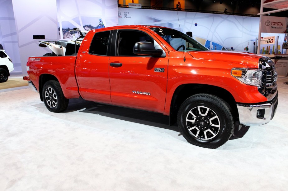 An orange 2017 Toyota Tundra parked at an auto show, an ATV in its bed.