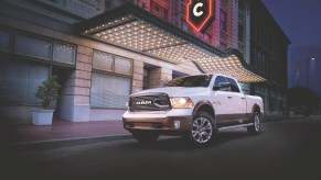 White Ram pickup truck parked in front of a city building with neon lights.