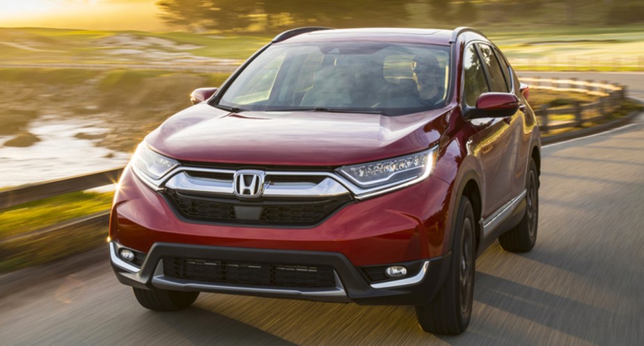 A red Honda CR-V is driving on the road.