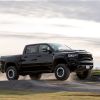 A black 2021 Ram 1500 TRX performance supercharged full-size pickup truck jumping off a dirt ramp