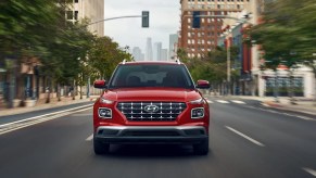 A red 2022 Hyundai Venue subcompact SUV is driving on the road.