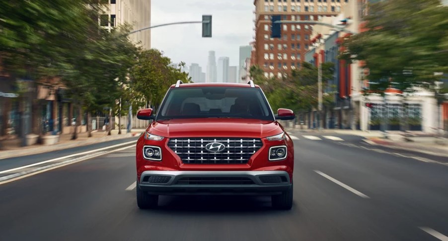 A red 2022 Hyundai Venue subcompact SUV is driving on the road.