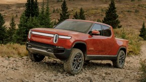 A red Rivian R1T electric truck is driving off-road.