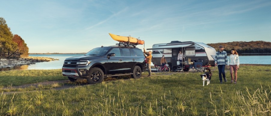 A blue 2023 Ford Expedition Max parked in front of a lake.