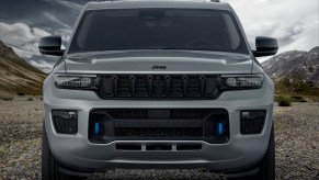 Closeup of the grille and front end of a Grand Cherokee 4xe plug-in hybrid SUV, mountains visible in the background.