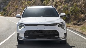 A white 2023 Kia Niro EV subcompact electric vehicle is driving on the road.