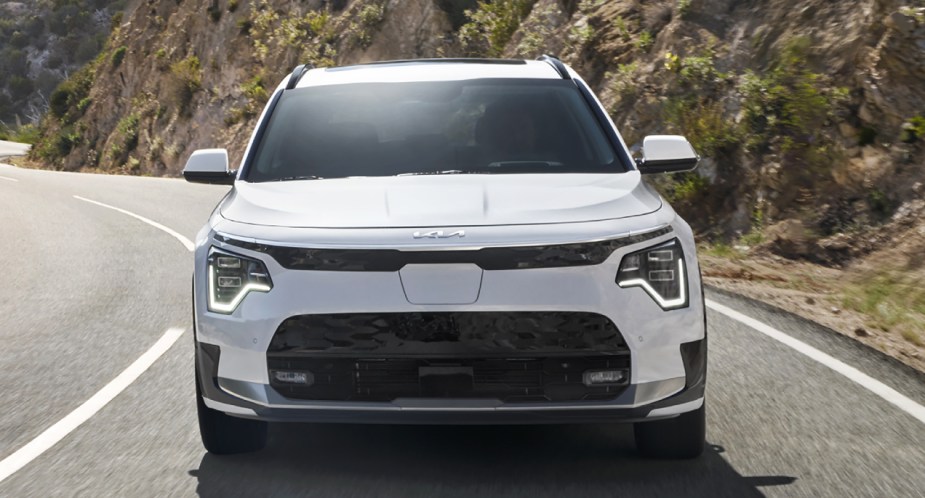 A white 2023 Kia Niro EV is driving on the road. 