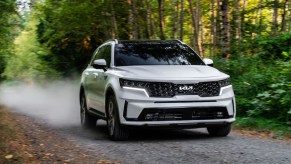 A 2023 Kia Sorento Hybrid driving down a dirt road in a wooded area.