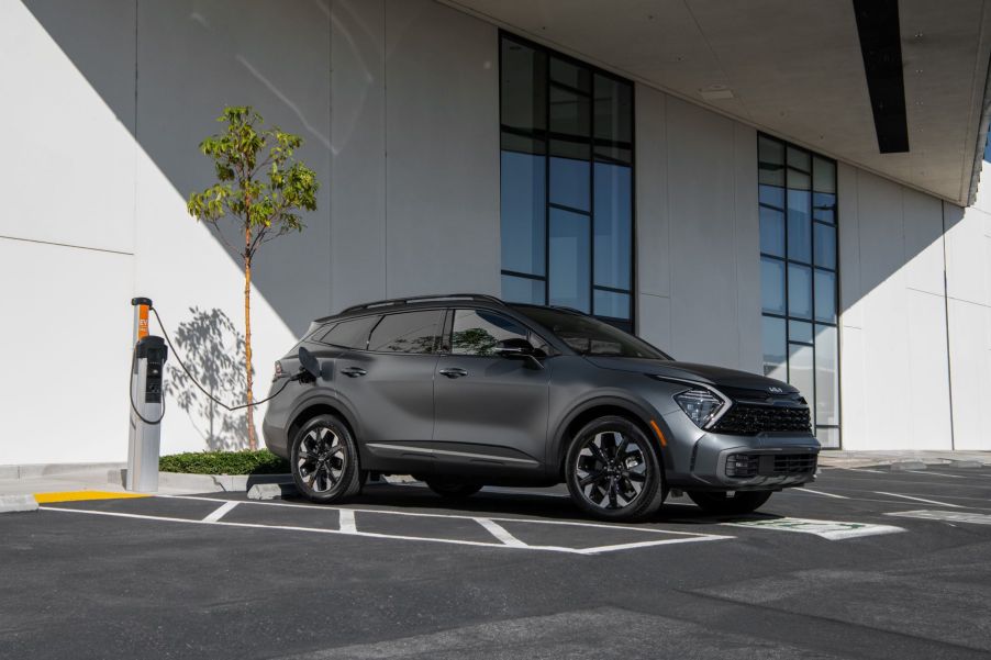 A gray 2023 Kia Sportage PHEV plug-in hybrid electric vehicle plugged into a charging station