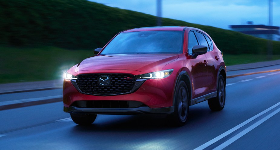 A red 2023 Mazda CX-5 small SUV is driving on the road. 