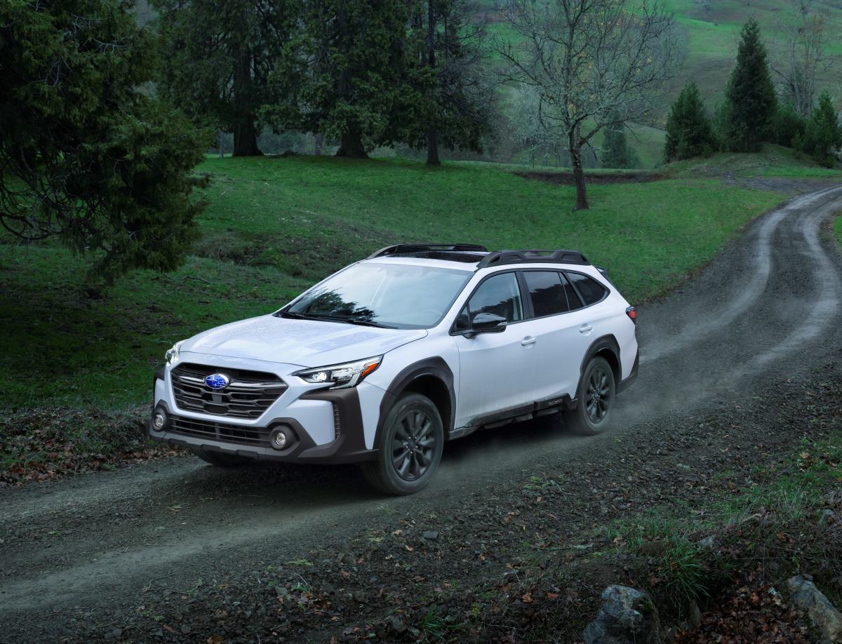 A white 2023 Subaru Outback driving along a gravel road