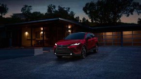 A red 2023 Toyota Venza parked in the driveway of an affluent home.