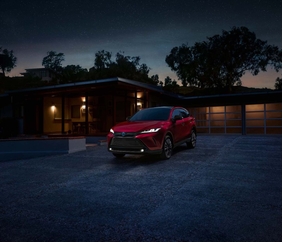 A red 2023 Toyota Venza parked in the driveway of an affluent home.