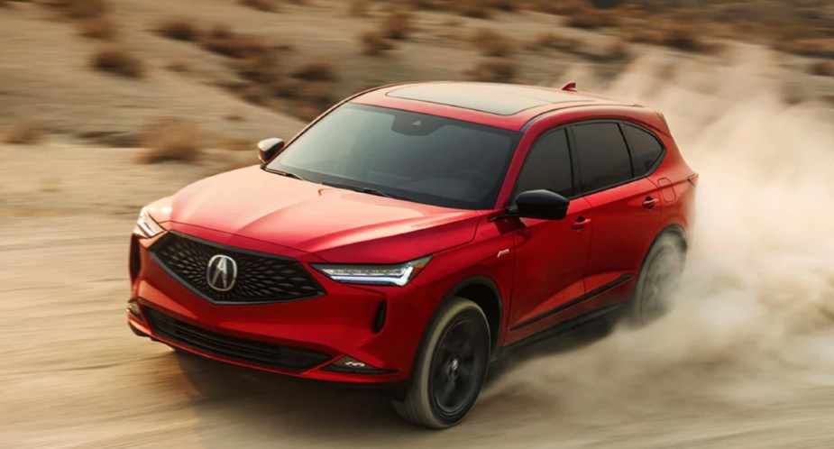 A red 2023 Acura MDX midsize SUV is driving off-road. 