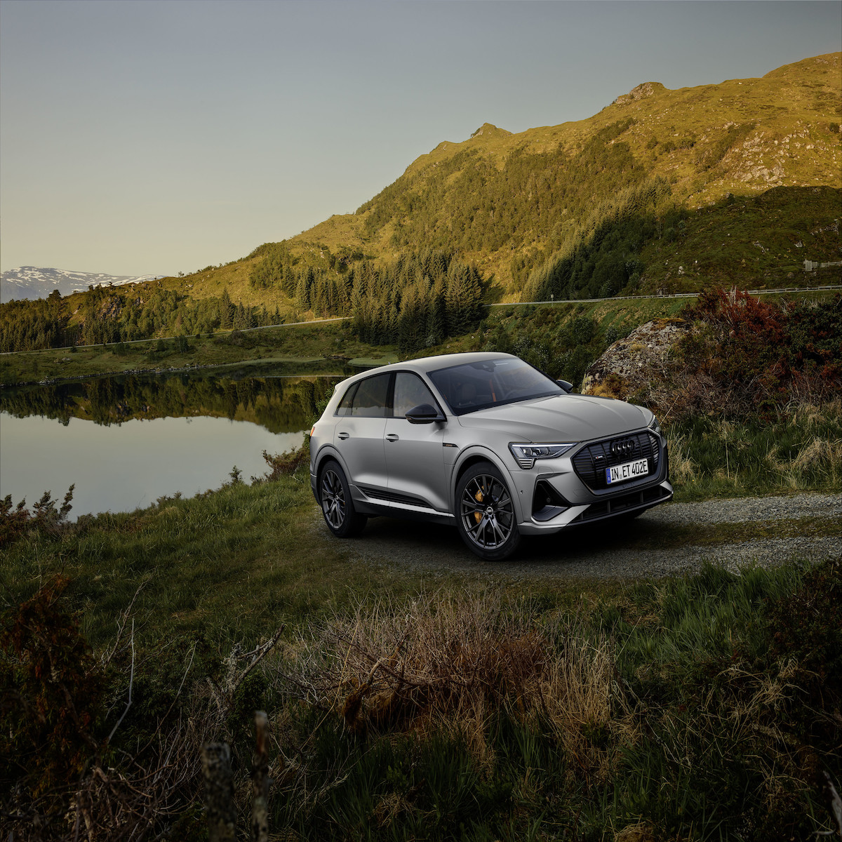 A silver 2023 Audi e-tron driving through the countryside.