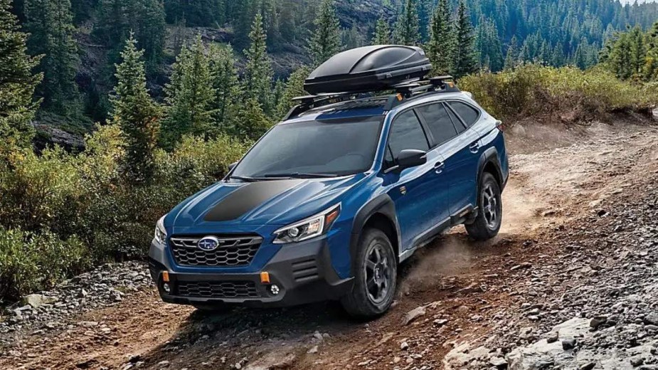 Blue 2023 Subaru Outback crossover SUV driving down a hill