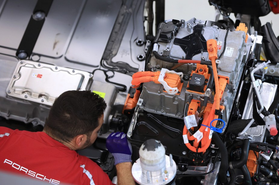 A person working on an electric drive train. However, how much does it cost to replace a battery in an electric vehicle like the one shown?