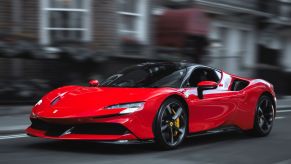 A red Ferrari SF90 Stradale plug-in hybrid electric vehicle (PHEV) coupe supercar driving in London