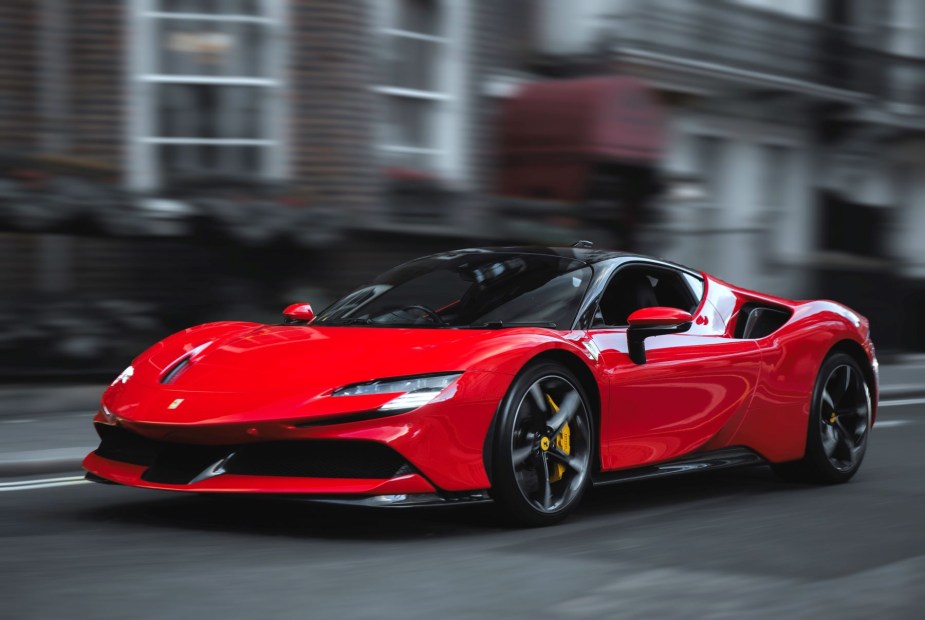 A red Ferrari SF90 Stradale plug-in hybrid electric vehicle (PHEV) coupe supercar driving in London