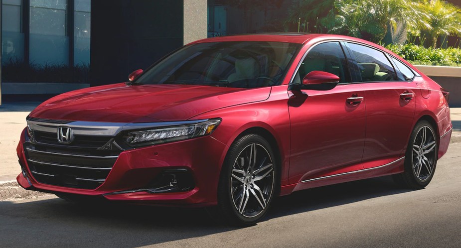 A red Honda Accord Hybrid midsize sedan is parked. 