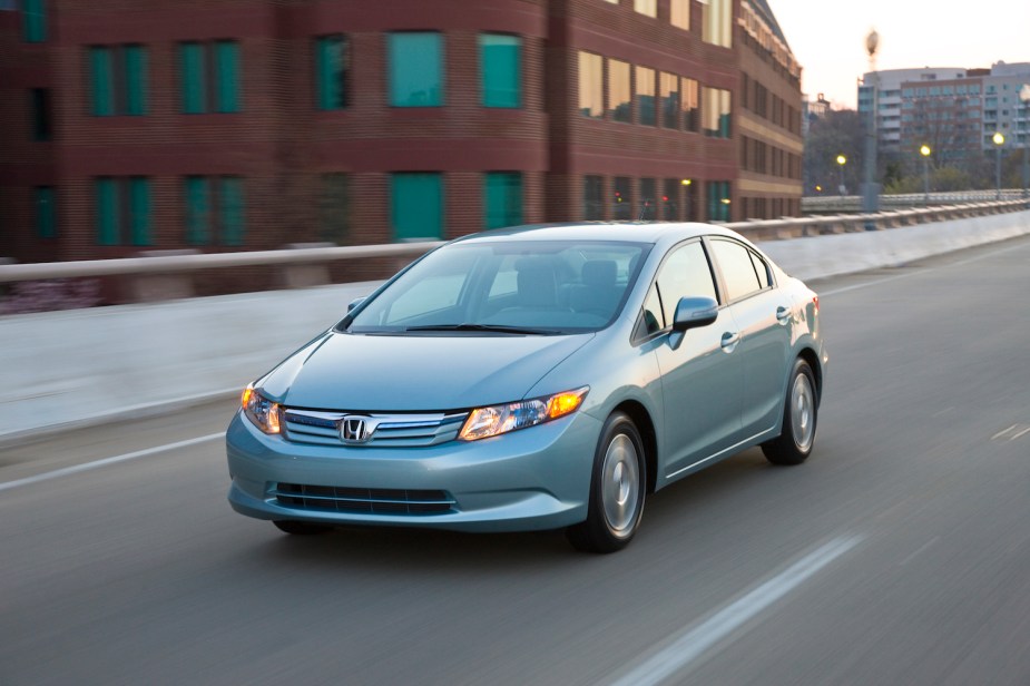 A silver Honda Civic Hybrid driving down a city street, the Honda Civic Hybrid is a fuel-efficient used hybrid sedan