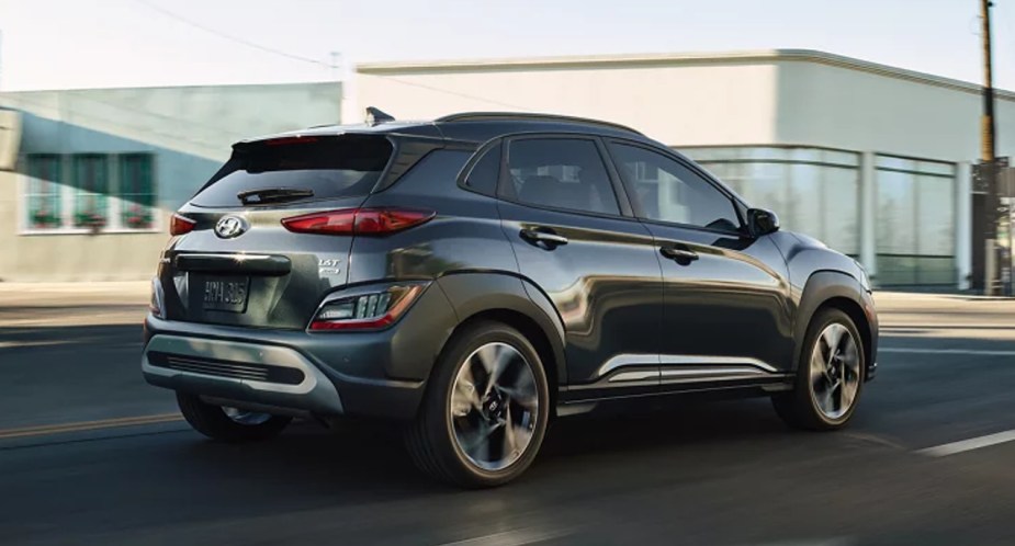 A green 2023 Hyundai Kona subcompact SUV is driving on the road. 