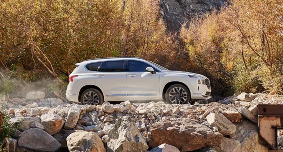 A white 2023 Hyundai Santa Fe midsize SUV is parked off-road. 