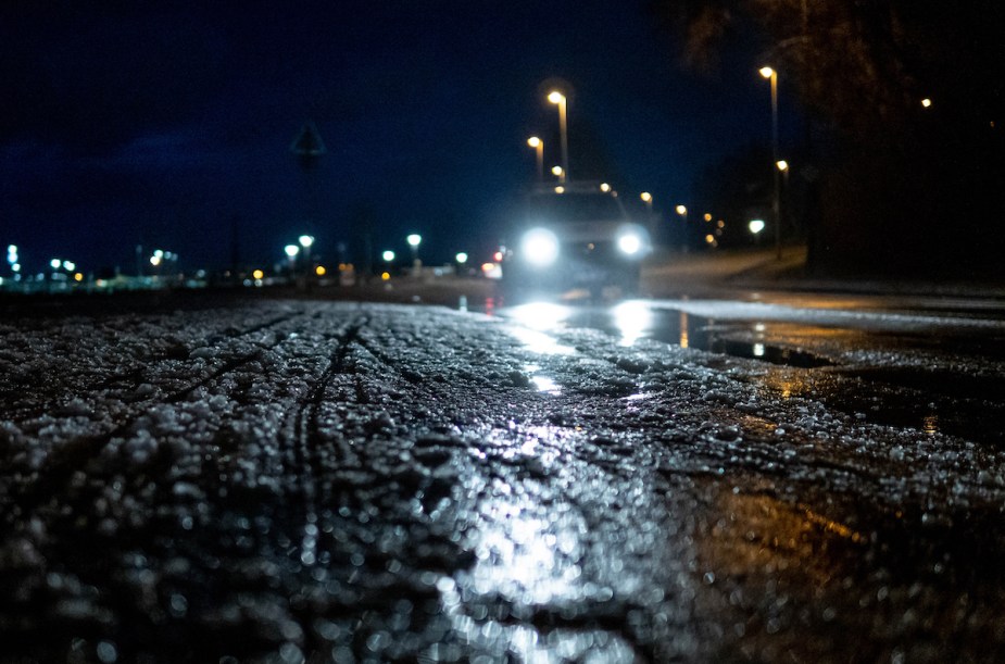 Ice covered road with headlights in the background, which is great for the best EVs for driving on ice and snow. 