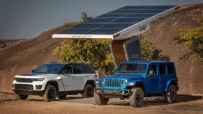 Jeep Grand Cherokee 4xe and Jeep Wrangler 4xe PHEVs plugged into a solar panel charging station