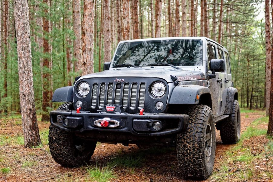 Gray modified Jeep Wrangler JK Unlimited SUV parked in the woods, trees visible in the background.