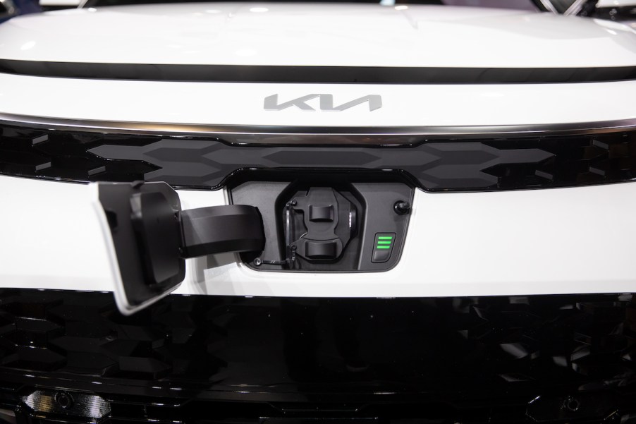 A white Kia Niro hybrid SUV front with charging port open.