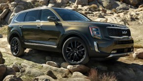 A green 2022 Kia Telluride midsize SUV is driving off-road.