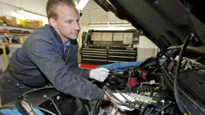 Mechanic, potentially checking glow plugs in a truck.