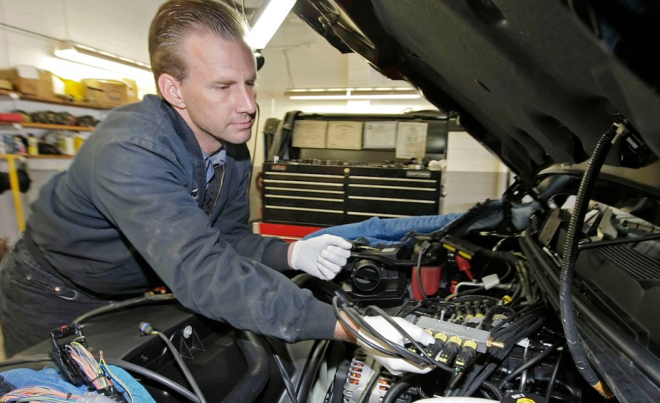 Mechanic, potentially checking glow plugs in a truck. 