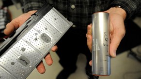 Closeup of a person's hands holding one cell of a Lithium-ion EV or hybrid battery and one cell of a Nickel Metal Hydride (NiMH) high-voltage traction battery.