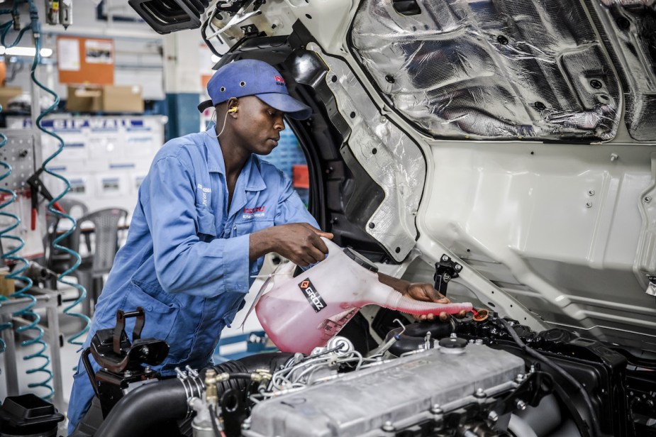 A person pouring antifreeze that could possibly have to clean up an antifreeze leak, 