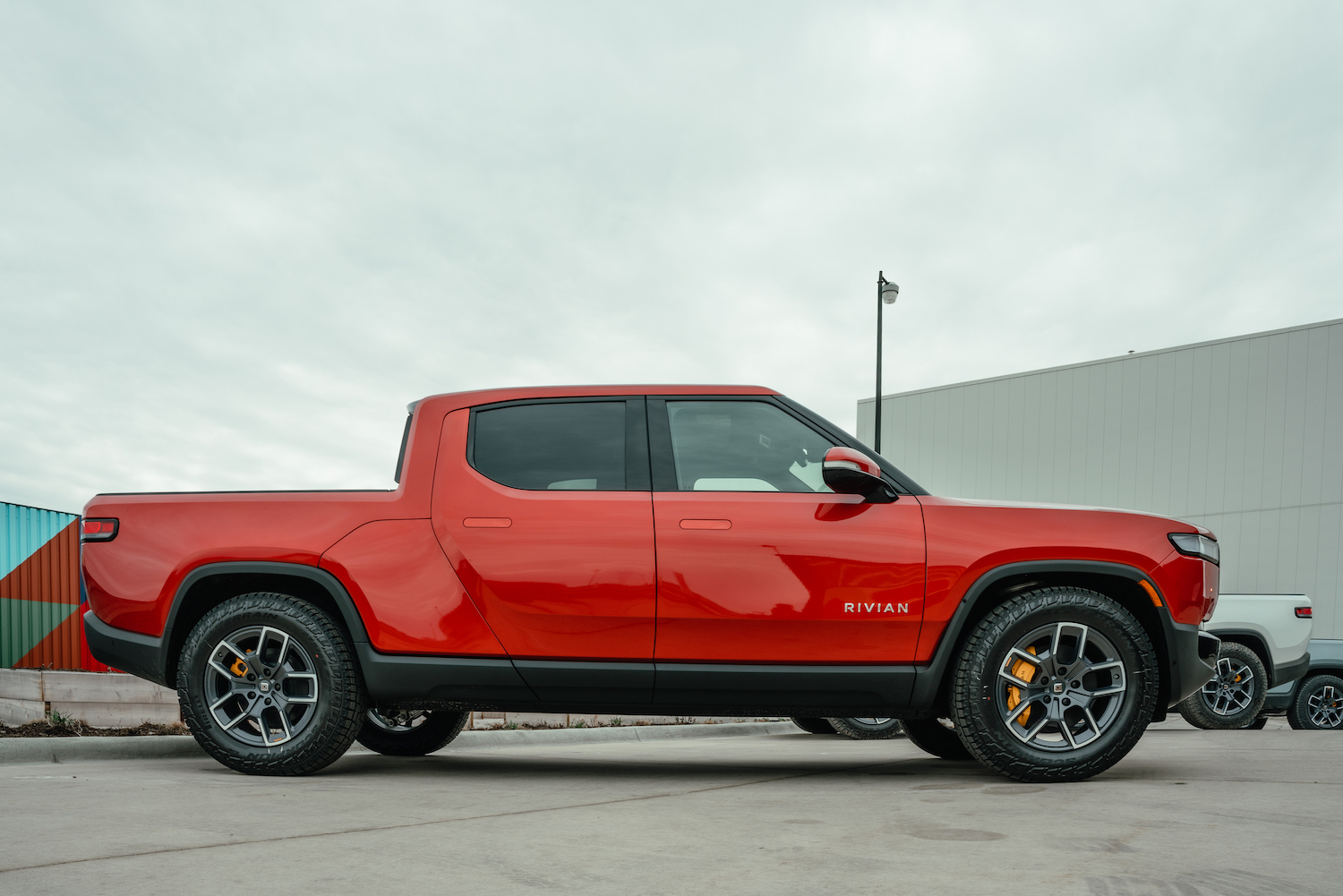 Red Rivian electric truck parked outside the manufacturer's factory.