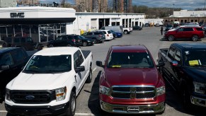 A row of reliable used pickup trucks including a Dodge Ram 1500 and Ford F-150, parked in a dealership lot.