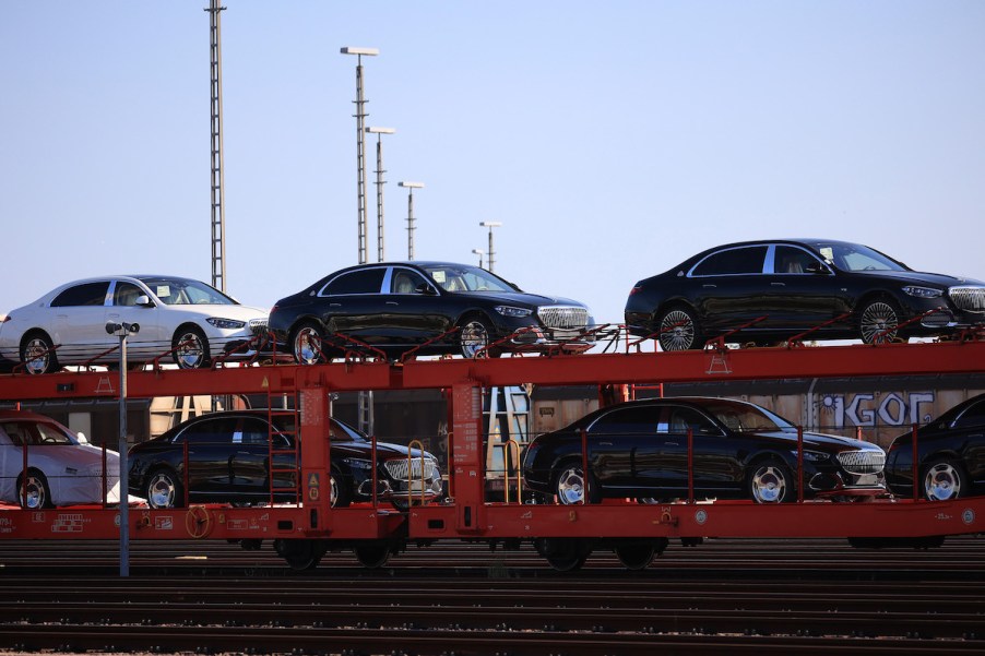 A person carrying a slew of cars where they are shipping a car.