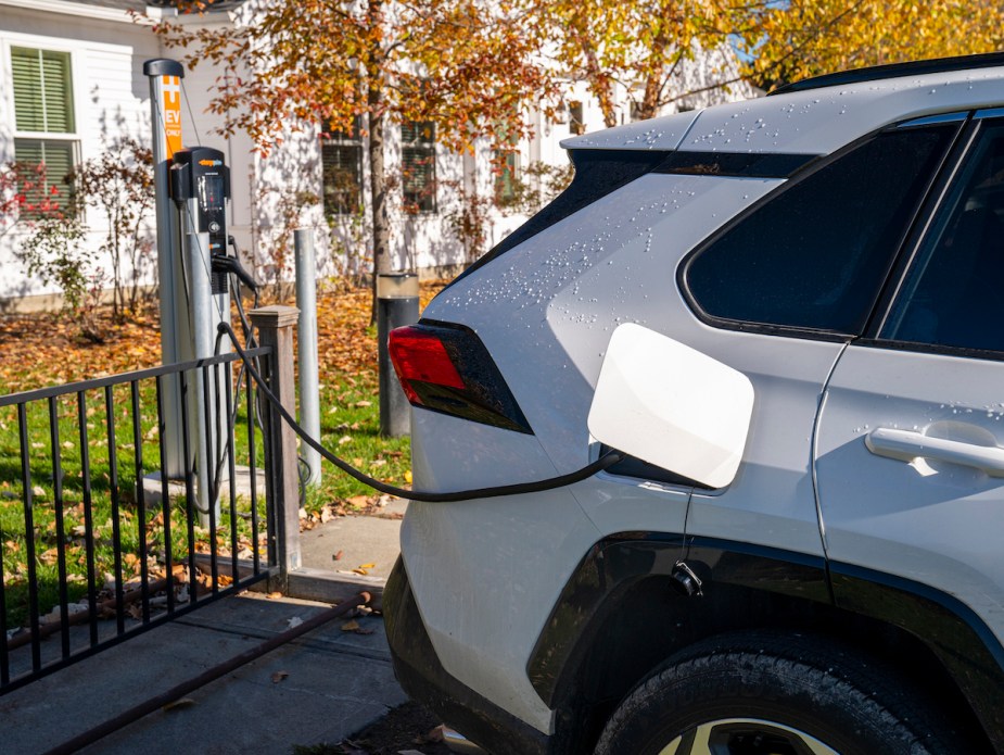 A white Toyota RAV4 Prime charging, which is a plug-in hybrid. 