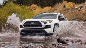 A white 2022 Toyota RAV4 small SUV is driving off-road.