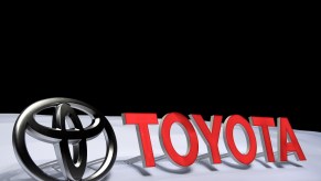 Toyota logo and the word Toyota on a white stage, with their shadows visible in the background.