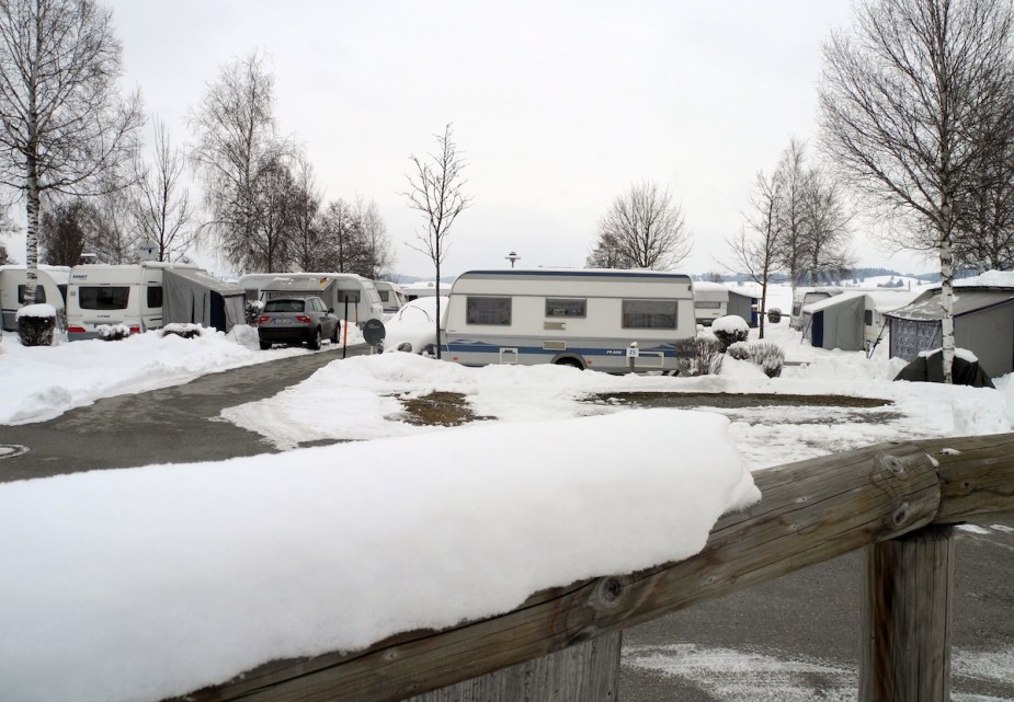 A group of campers parked in the snow, potentially winterizing your camper if parked here would be a good idea. 