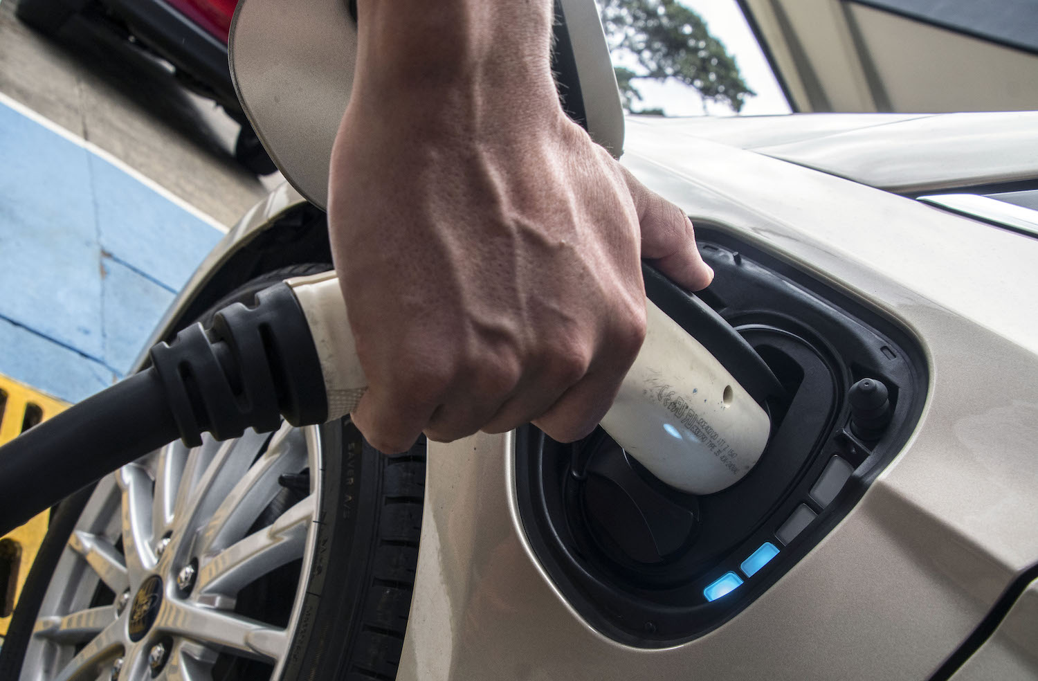 A person's hand connecting a high-speed electric charger to an electric vehicle's upgraded long range battery pack.