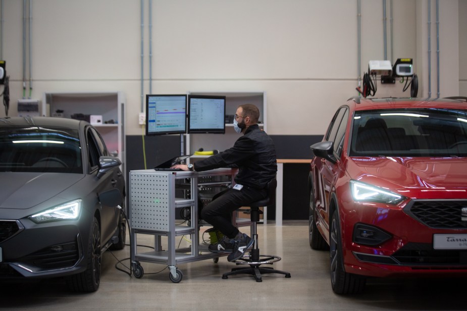 A hybrid and electric vehicle lithium-ion battery technician reads a computer read out in a garage.