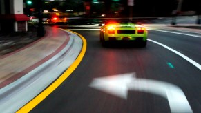 A green Lamborghini turns left at an intersection.