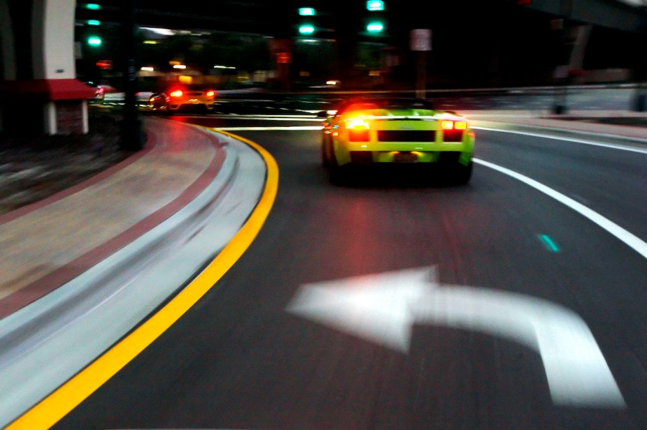 A green Lamborghini turns left at an intersection.