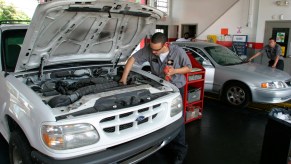 A person changing the oil, potentially with high mileage oil.