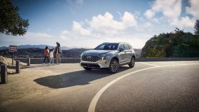 A silver gray 2023 Hyundai Santa Fe Plug-In Hybrid midsize crossover SUV model parked by a cliff overlook